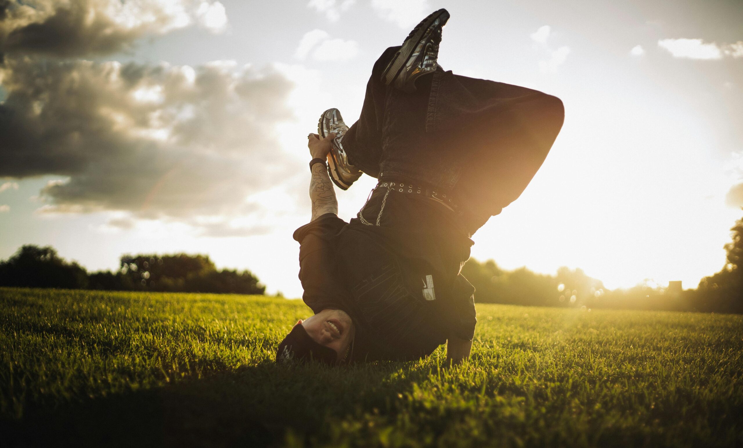 Dynamisches Bild eines Breakdancers, der in einer sonnigen Parklandschaft einen Headspin ausführt.