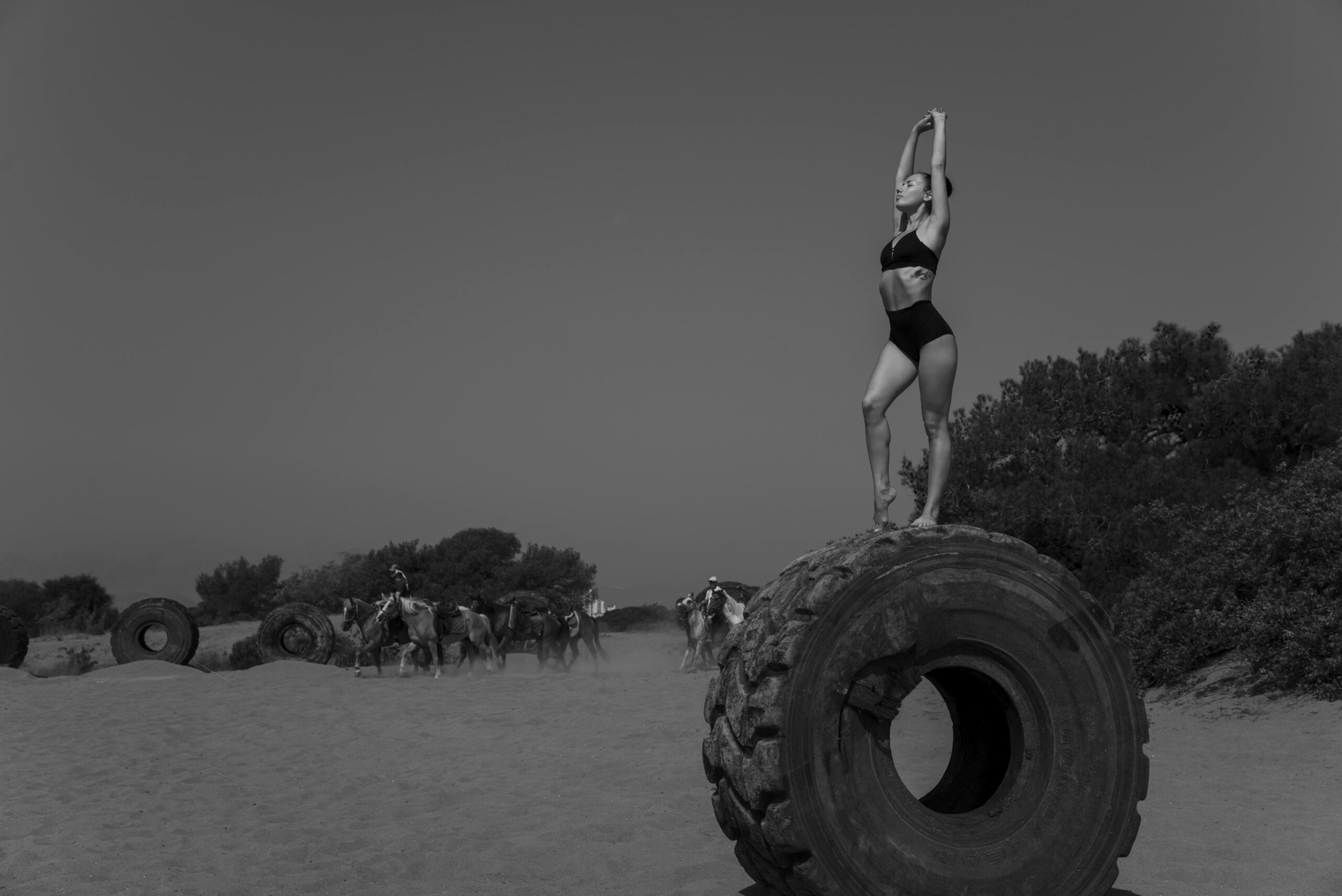 Eine Frau in Badebekleidung posiert anmutig auf einem Reifen in einer w&Atilde;&frac14;sten&Atilde;&curren;hnlichen Umgebung.