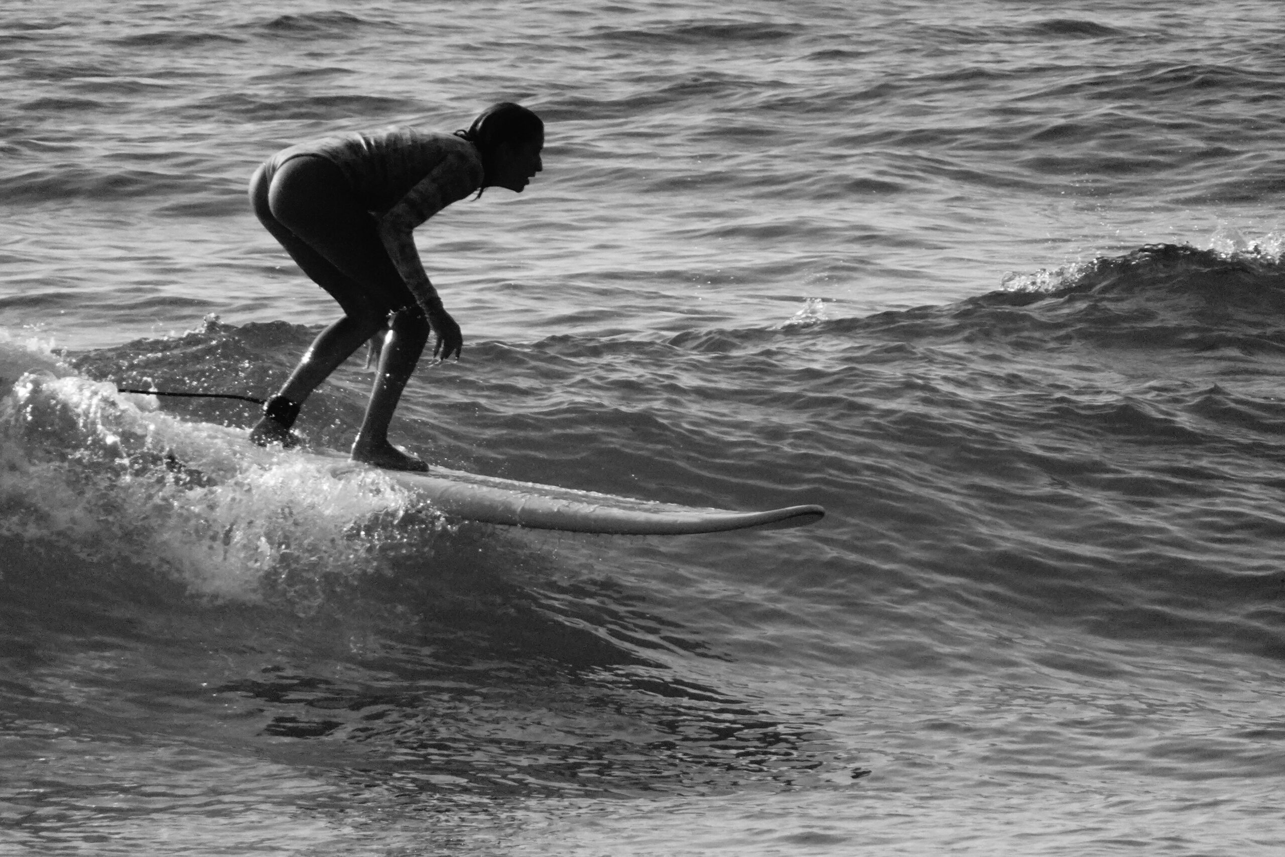 Silhouette eines Surfers, der in monochromer Umgebung eine Welle fängt.
