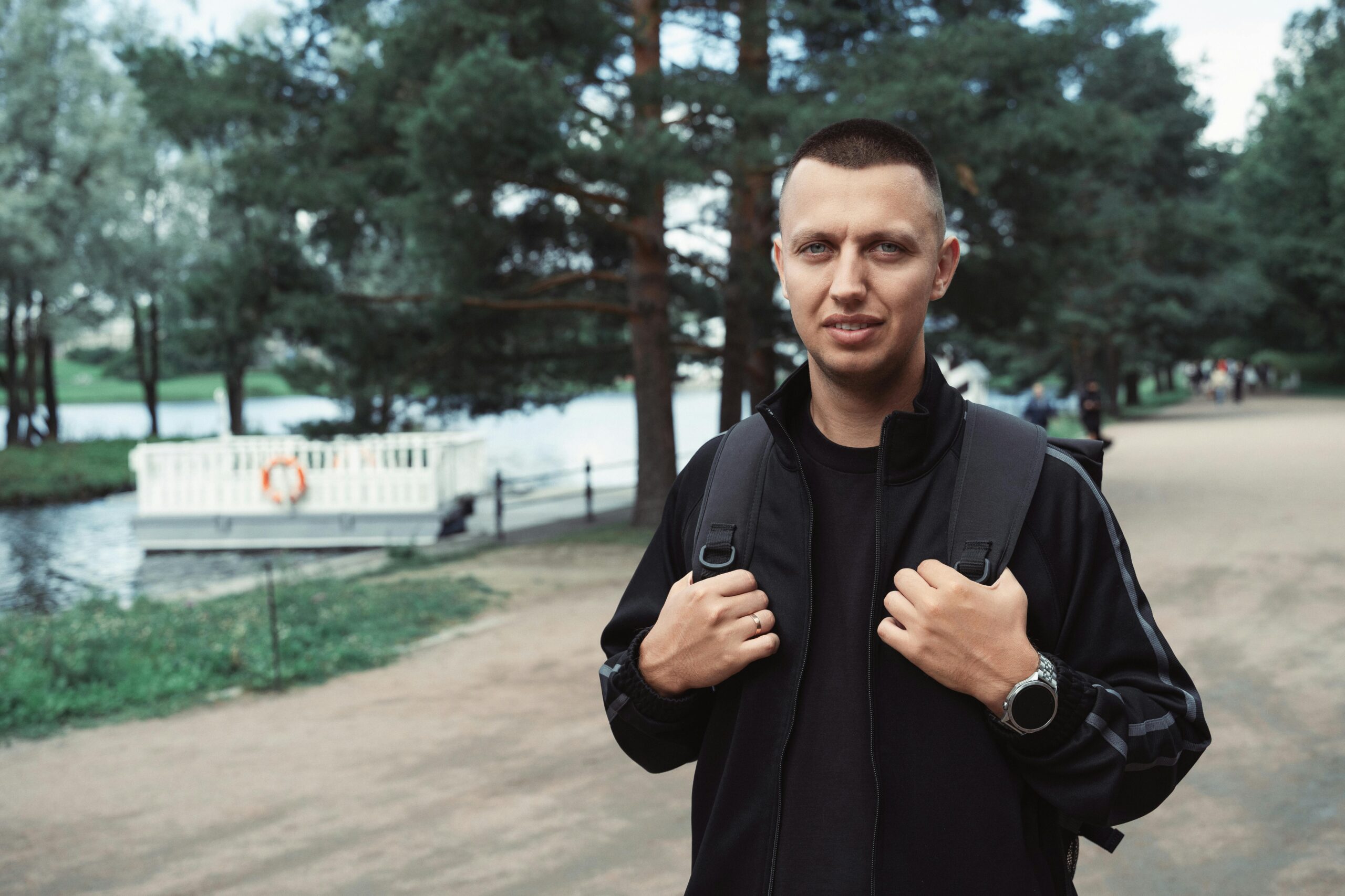 L&Atilde;&curren;ssiges Portr&Atilde;&curren;t eines jungen Mannes mit Rucksack, der einen Spaziergang in einem &Atilde;&frac14;ppigen Park im Freien genie&Atilde;Ÿt.