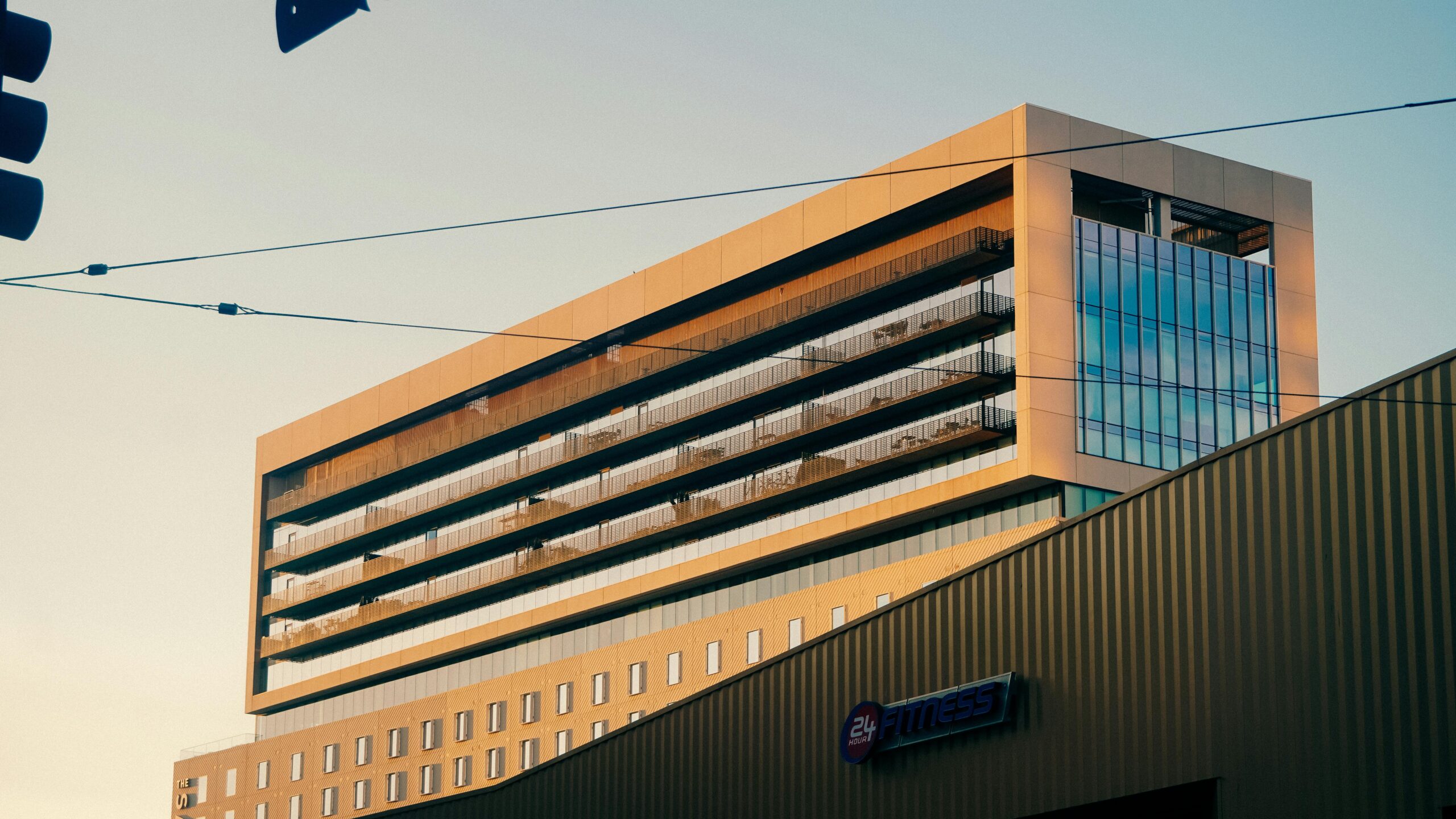 Die Außenansicht eines modernen Bürogebäudes wurde bei Sonnenuntergang fotografiert und zeigt ein Fitnessstudio-Schild.